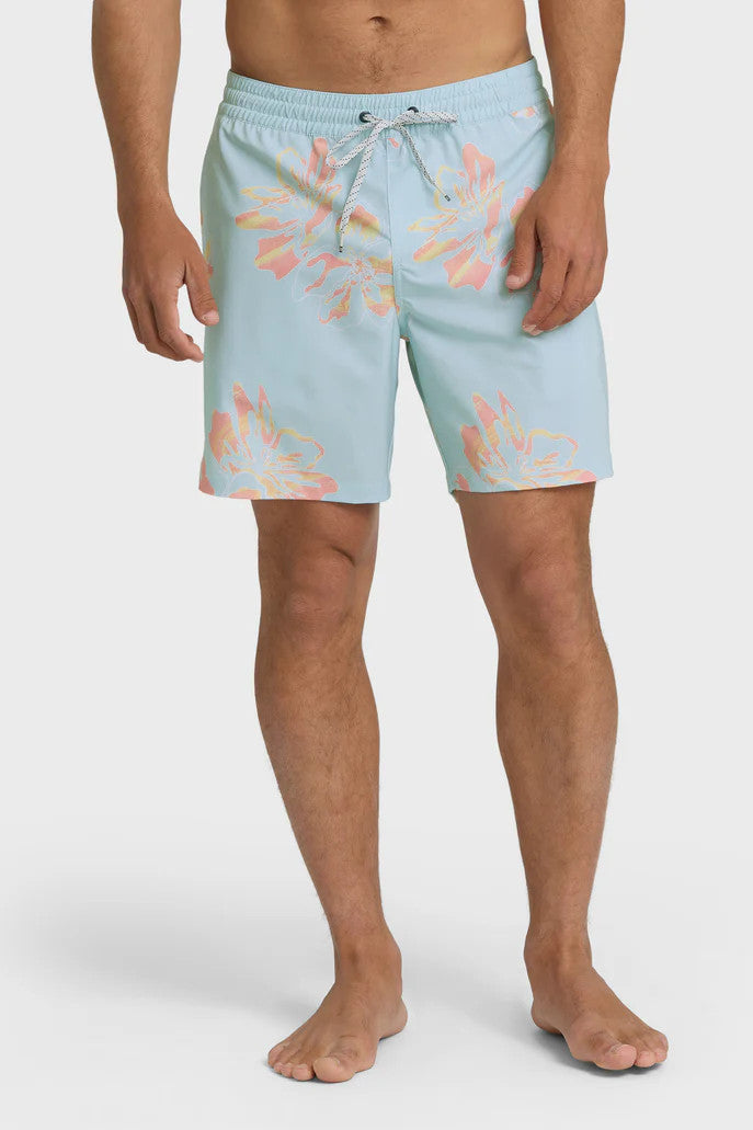 Man wearing light blue swim trunks with a yellow and orange oversized floral pattern and elastic waistband with drawstring on a white background