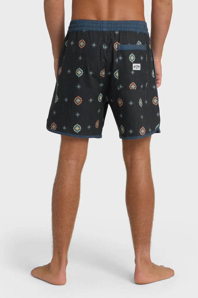 Back view of a man wearing charcoal swim trunks with a light blue and orange pattern pattern and contrasting navy elastic waistband with drawstring on a white background