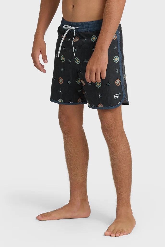 Man wearing charcoal swim trunks with a light blue and orange pattern pattern and contrasting navy elastic waistband with drawstring on a white background