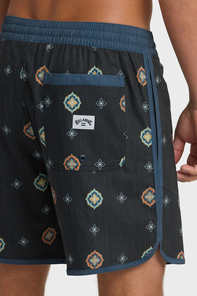 Man wearing charcoal swim trunks with a light blue and orange pattern pattern and contrasting navy elastic waistband with drawstring on a white background