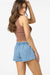 Woman wearing a brown tank top and blue denim shorts on a white background