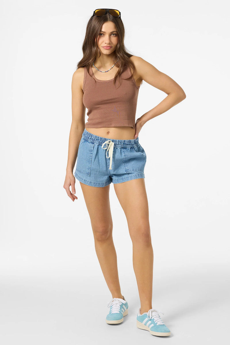 Woman wearing a brown tank top and blue denim shorts on a white background