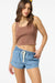 Woman wearing a brown tank top and blue denim shorts on a white background