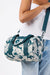 Person holding a floral duffel bag with dark teal straps on a white background