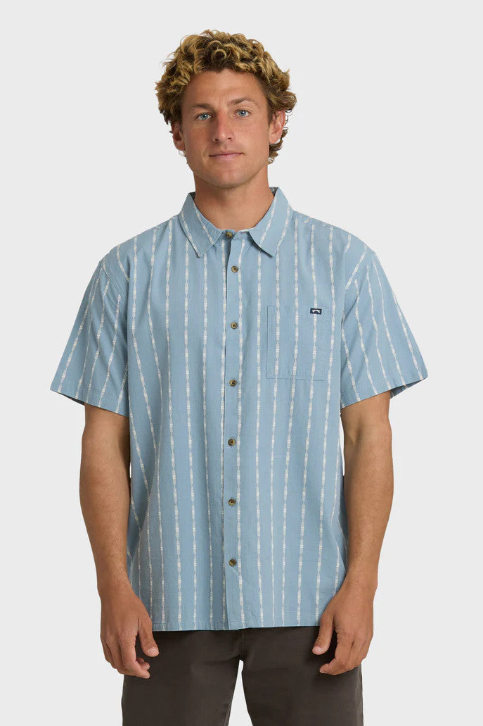 Man wearing a blue short-sleeve button-up shirt with a white stripe pattern on a white background