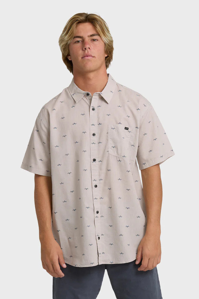 Man wearing a patterned light pink button-up collared shirt on a white background