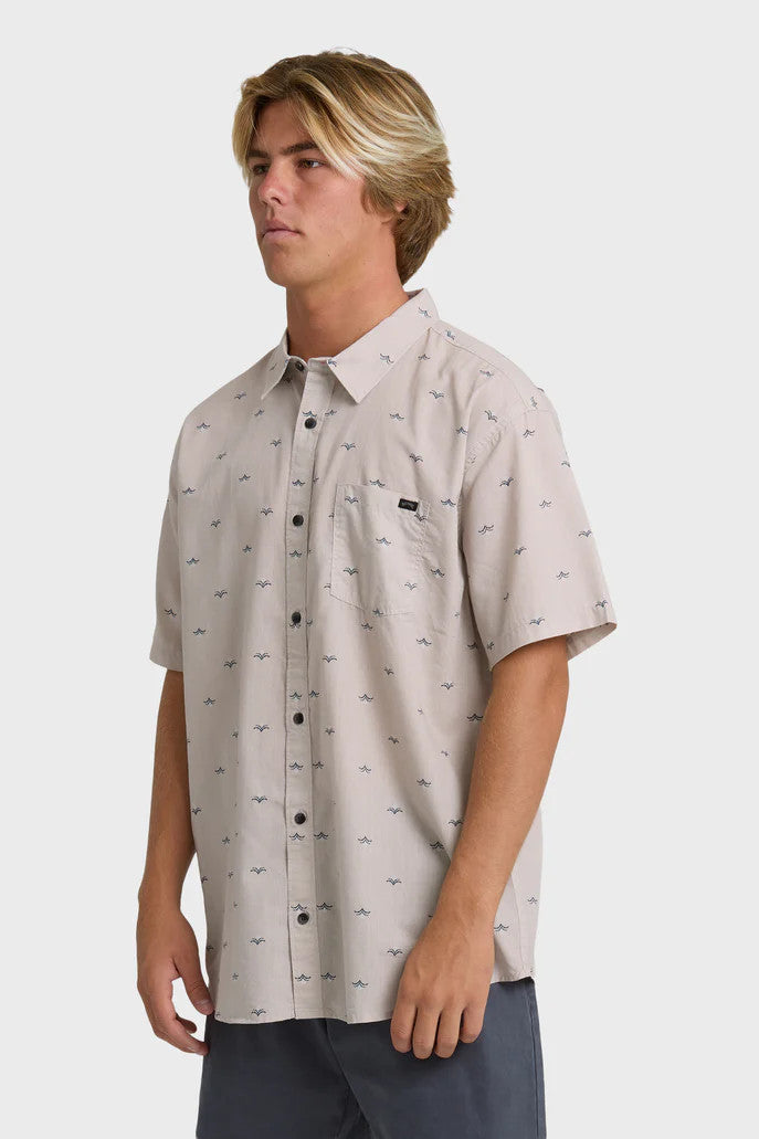 Man wearing a patterned light pink button-up collared shirt on a white background