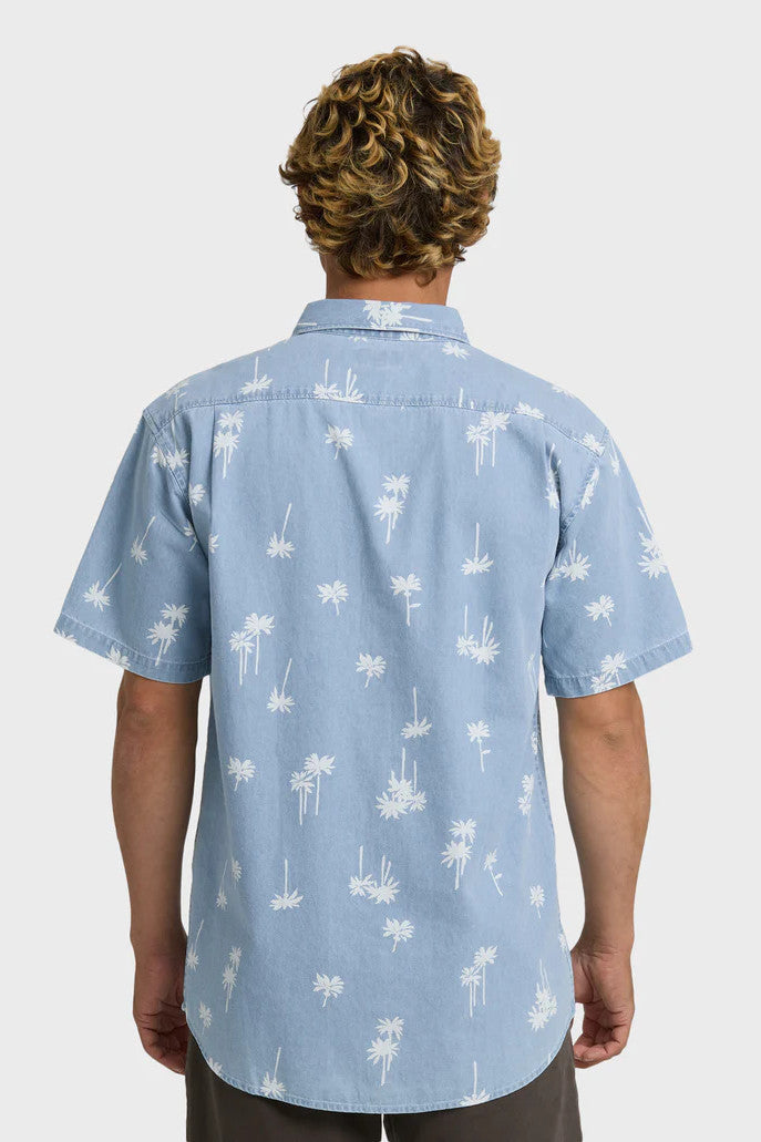 Back view of a man wearing a light blue button-up shirt with white palm tree pattern on a white background