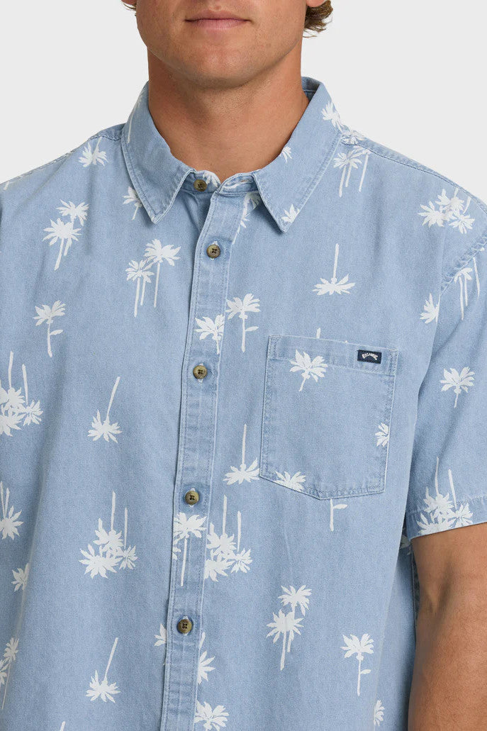 Man wearing a light blue button-up shirt with white palm tree pattern on a white background