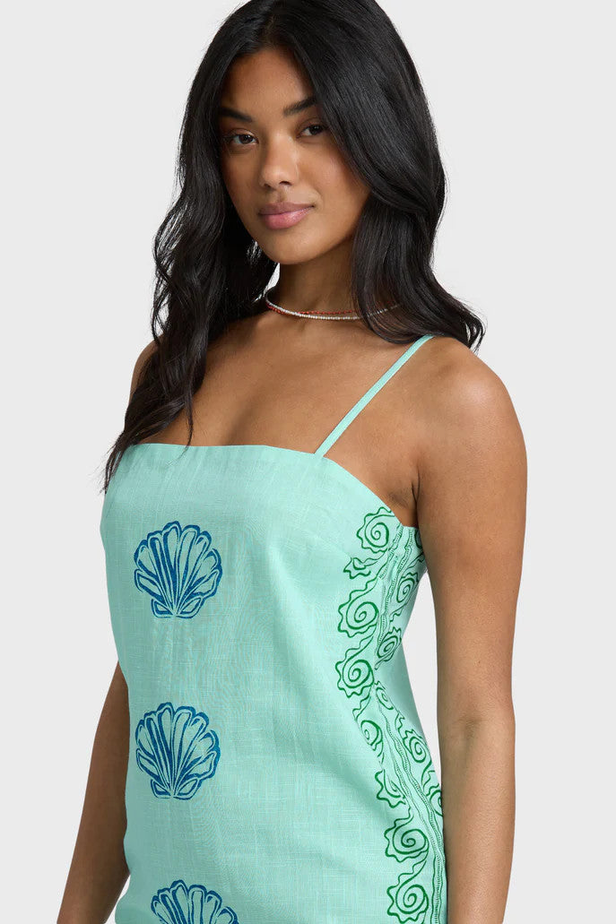 Woman wearing a light blue dress with shell patterns on a white background