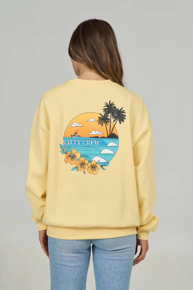 Back view of a woman wearing a yellow sweatshirt with a 'Salty Crew' graphic of a ship at sea with palm trees and flowers on a gray background