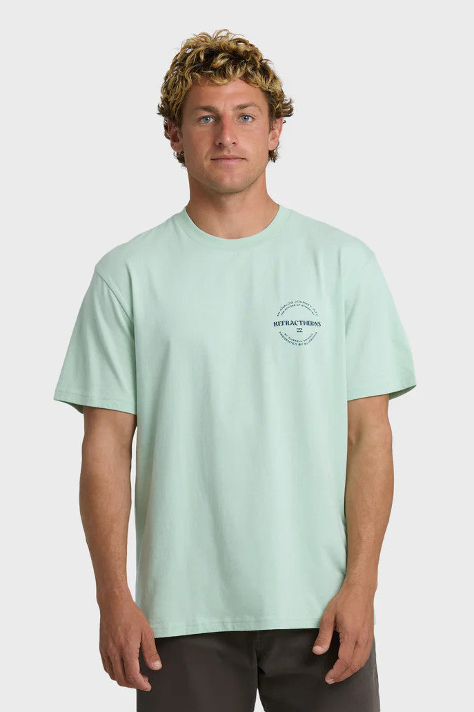 Man wearing a light green t-shirt with a chest logo on a white background