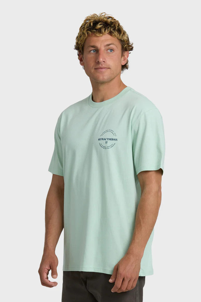 Man wearing a light green t-shirt with a chest logo on a white background