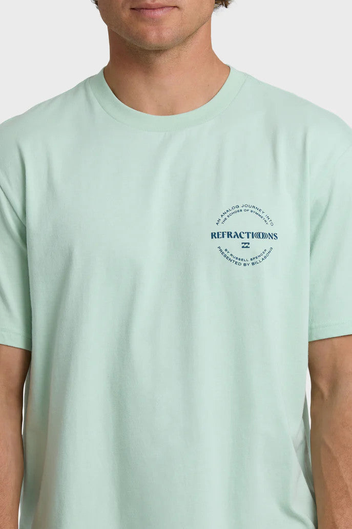 Man wearing a light green t-shirt with a chest logo on a white background