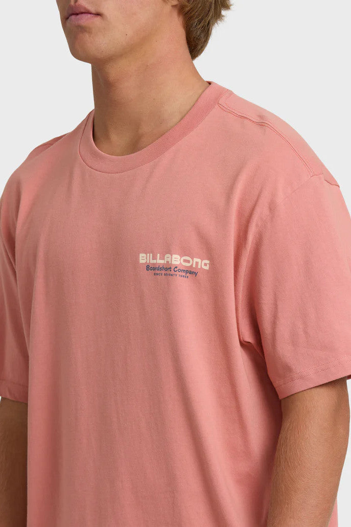 Person wearing a pink t-shirt with Billabong logo on a white background