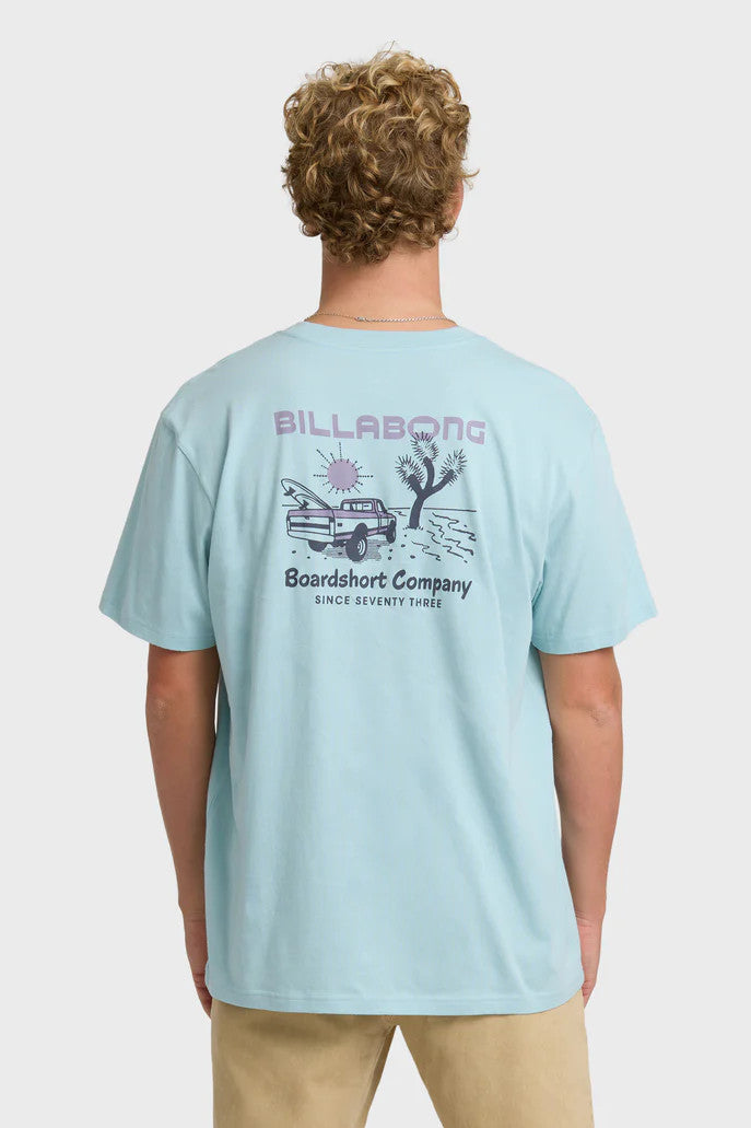 Person wearing a light blue Billabong t-shirt with a graphic design on the back.