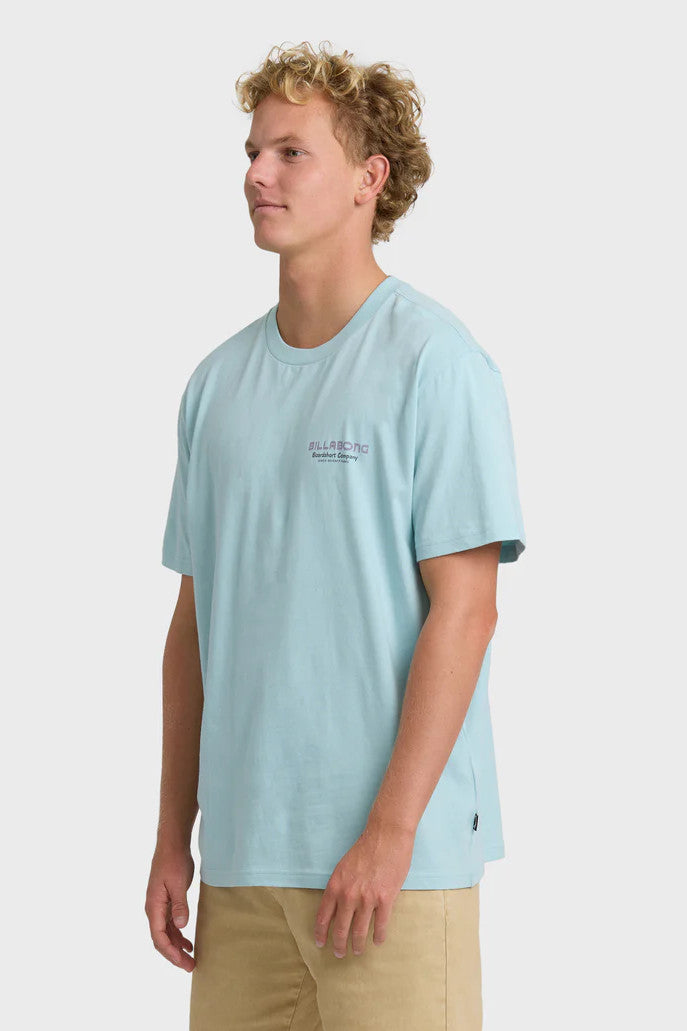 Man wearing a light blue t-shirt with a logo on a white background