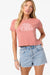 Woman wearing a pink O'Neill t-shirt and denim shorts on a white background