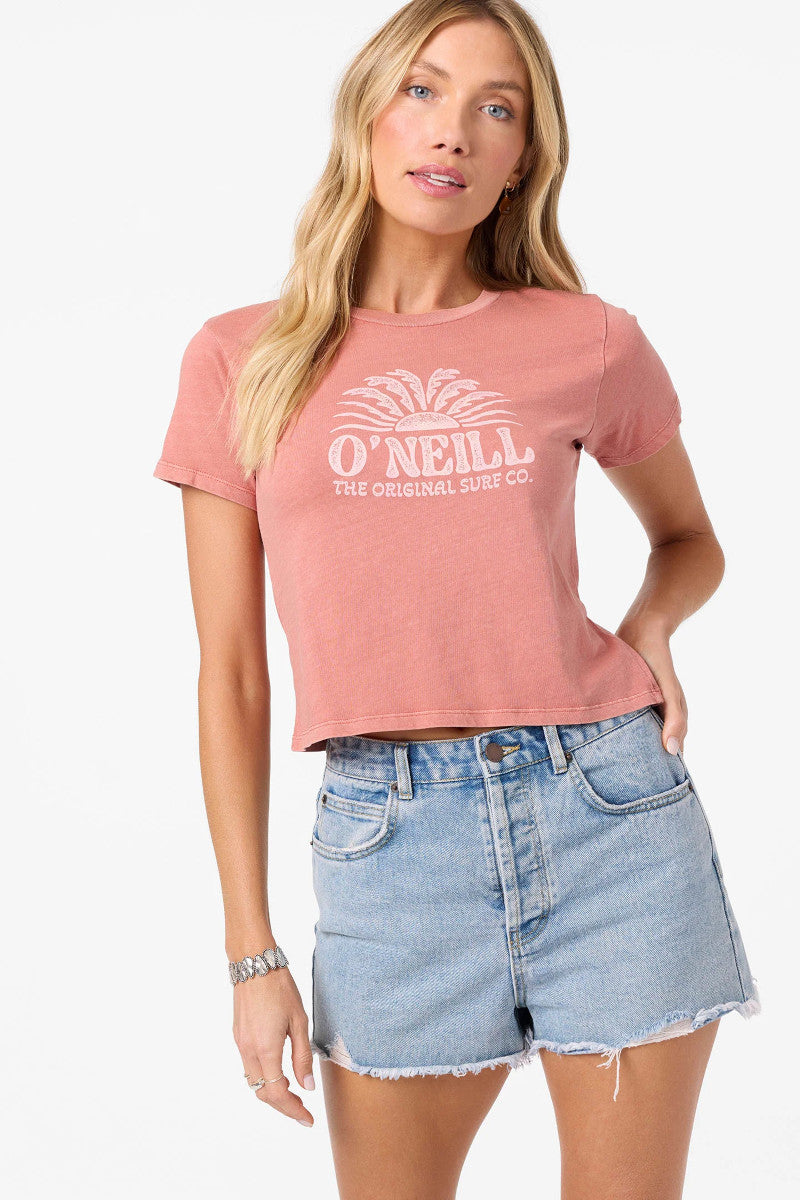Woman wearing a pink O'Neill t-shirt and denim shorts on a white background