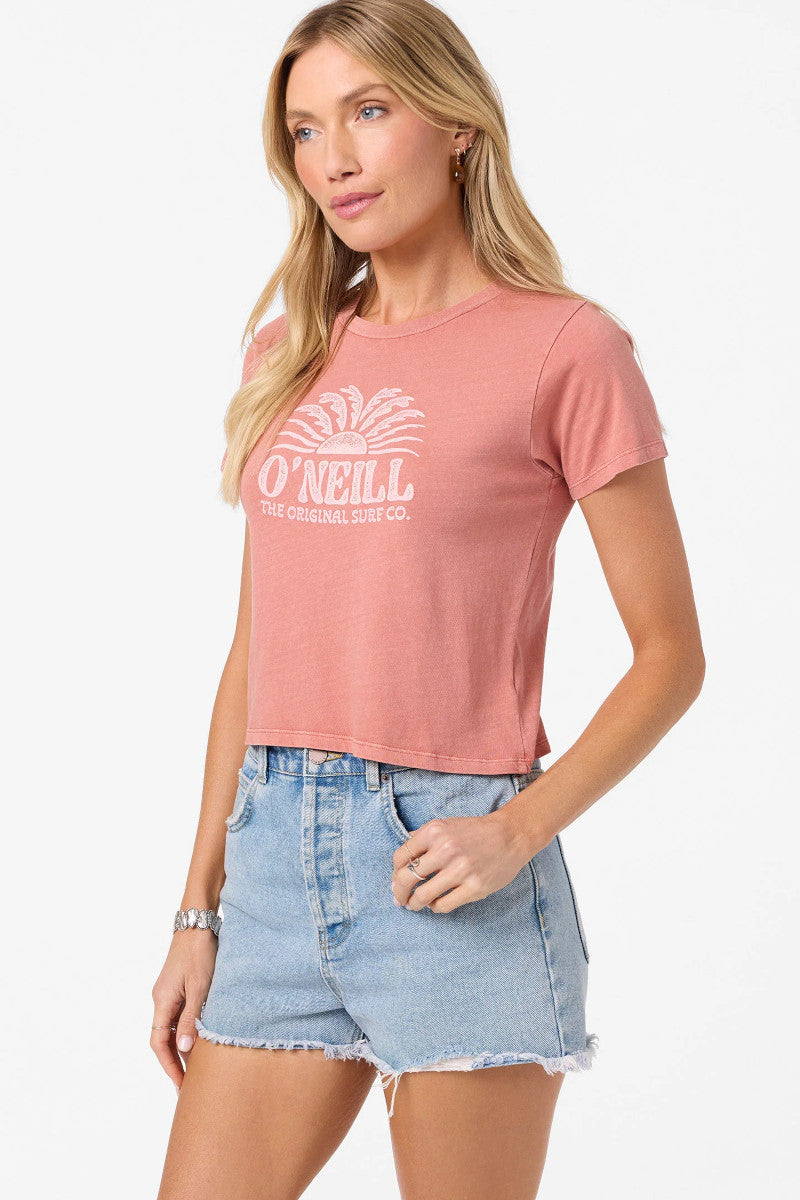 Woman wearing a pink O'Neill t-shirt and denim shorts on a white background