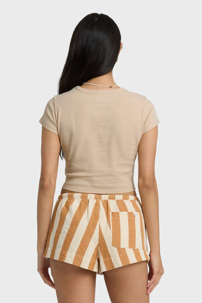 Back view of a woman wearing a beige crop top and striped shorts on a white background