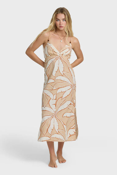 Woman wearing a beige and white tropical print dress on a white background