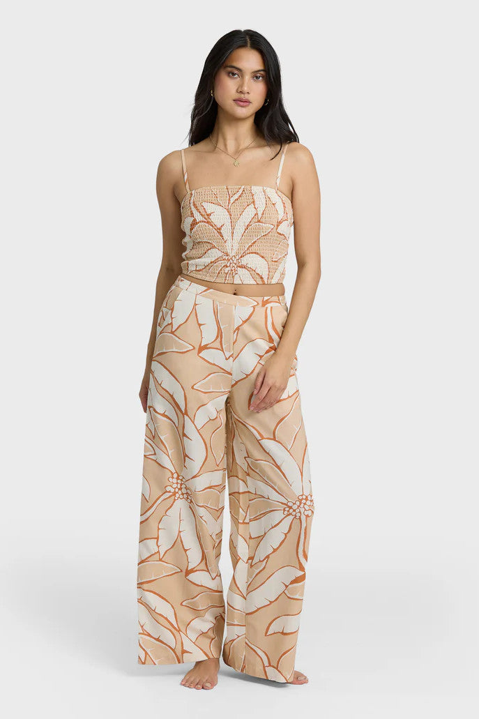 Woman wearing a beige and white tropical patterned outfit on a white background