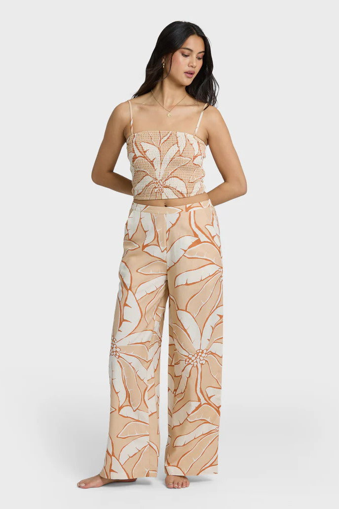 Woman wearing a beige and white tropical patterned outfit on a white background