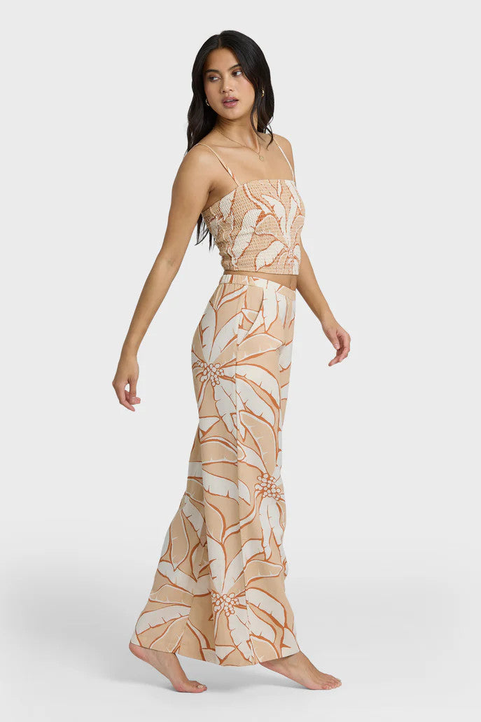 Woman wearing a beige and white tropical patterned outfit on a white background