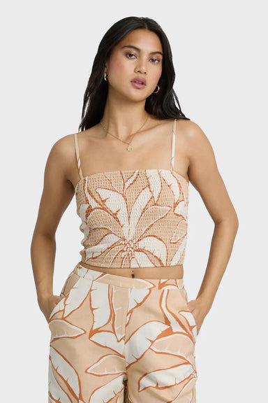 Woman wearing a beige and white tropical print top and pants on a white background