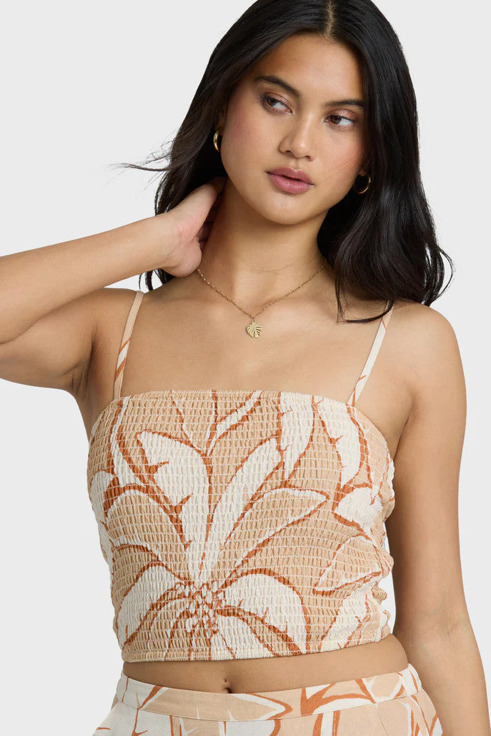 Woman wearing a tropical print top with a plain background