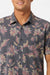 Man wearing a floral patterned shirt with a white background