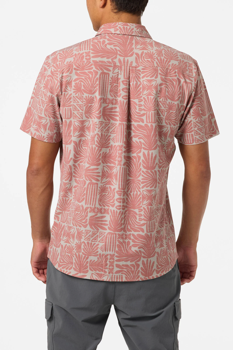 Person wearing a patterned pink shirt with gray pants on a white background