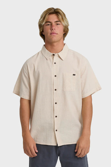 Man wearing a beige short-sleeve button-up shirt on a white background