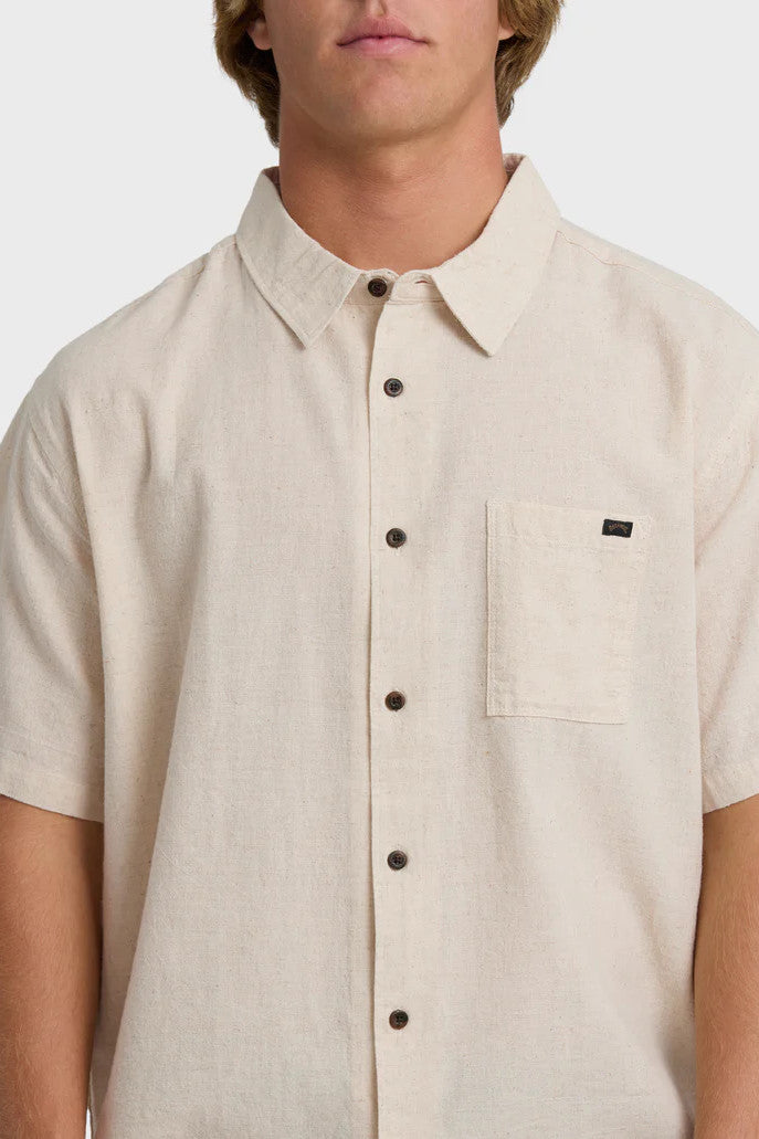 Beige button-up shirt worn by a person on a white background