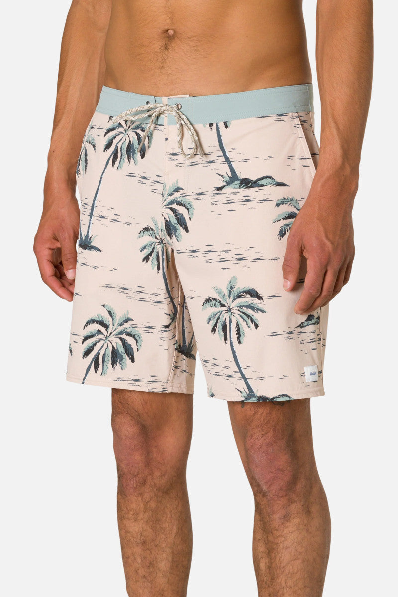 Person wearing a tropical print shorts with palm trees on a plain background