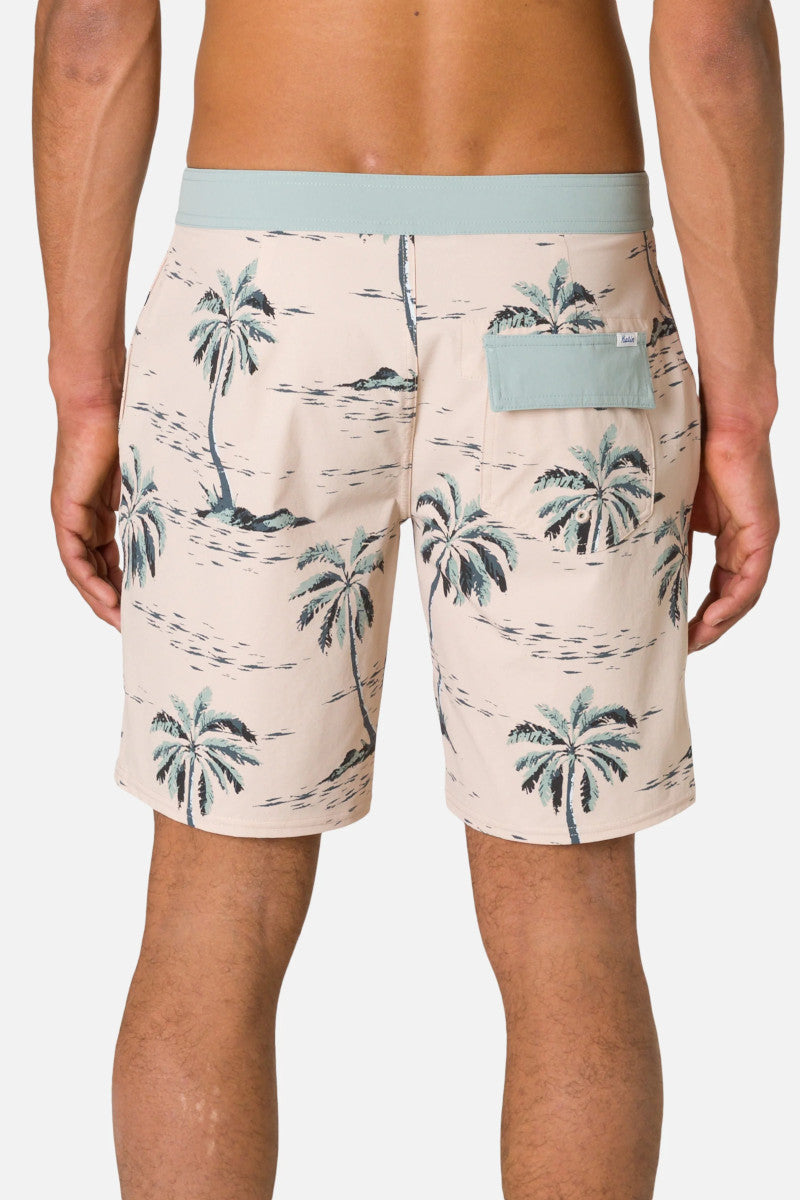Beige shorts with palm tree pattern worn by a person on a light gray background