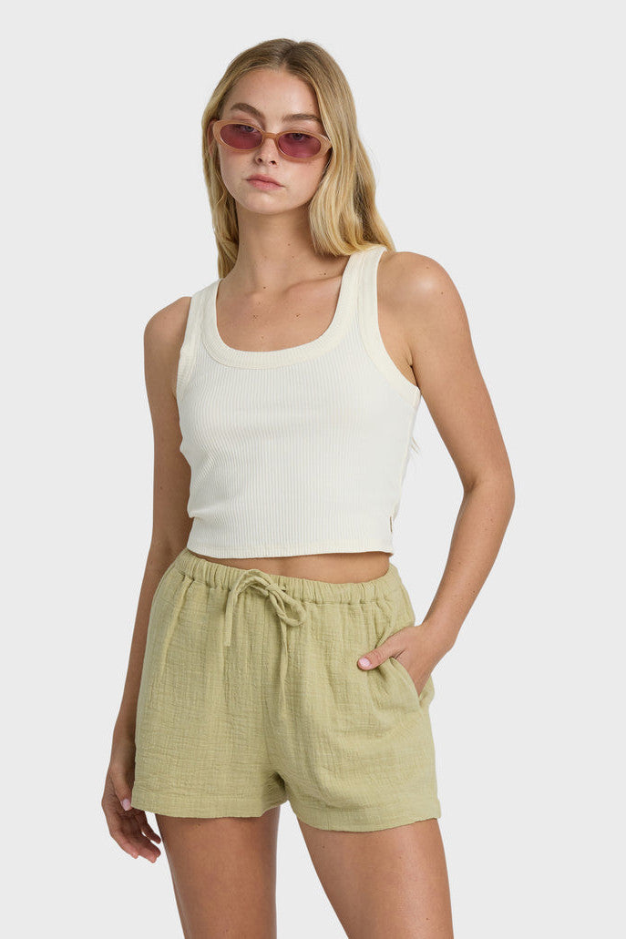 Woman wearing a white tank top and green shorts on a white background