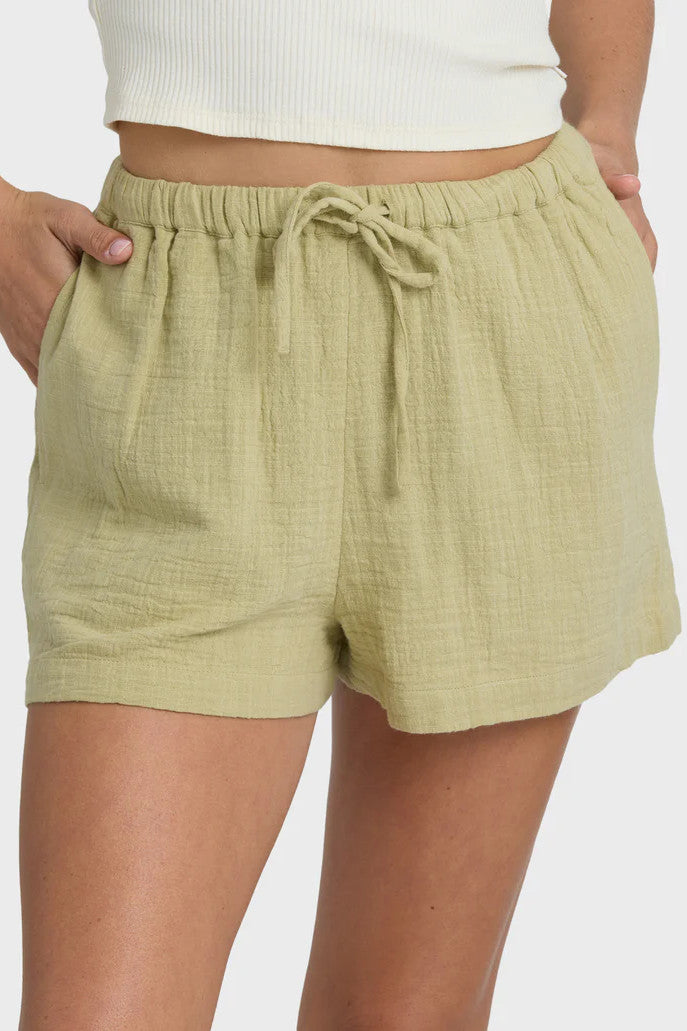 Woman wearing a white tank top and green shorts on a white background