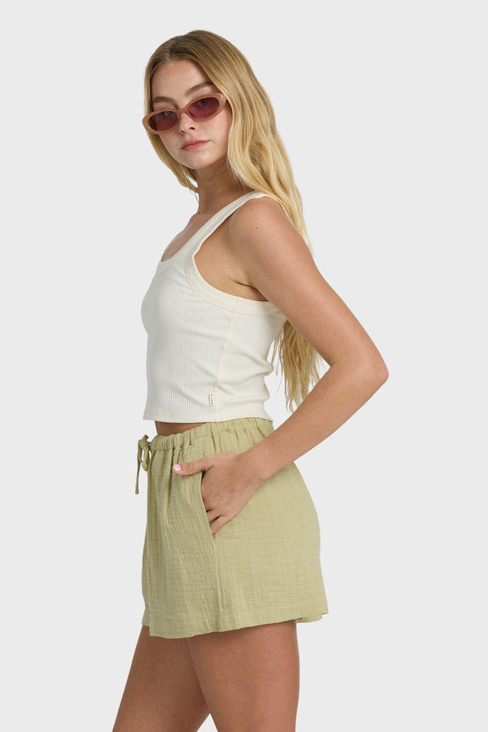 Woman wearing a white tank top and green shorts on a white background