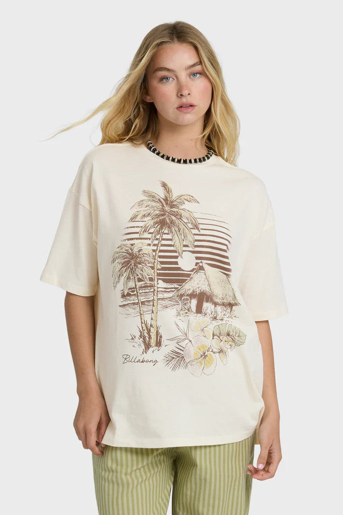 Woman wearing a cream t-shirt with a palm tree and surf shack graphic design on a white background