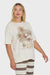 Woman wearing a cream t-shirt with a palm tree and surf shack graphic design and striped pants on a white background